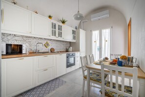 Una cocina moderna con armarios blancos, microondas, horno y comedor con mesa y sillas.