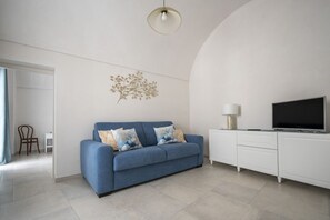 Ein modernes Wohnzimmer mit einem blauen Sofa, einem Flachbildfernseher, einem weißen Schrank und einer Wanddekoration.