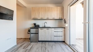 Une cuisine moderne avec des meubles de couleur bois clair, un réfrigérateur en acier inoxydable et un plan de travail noir.