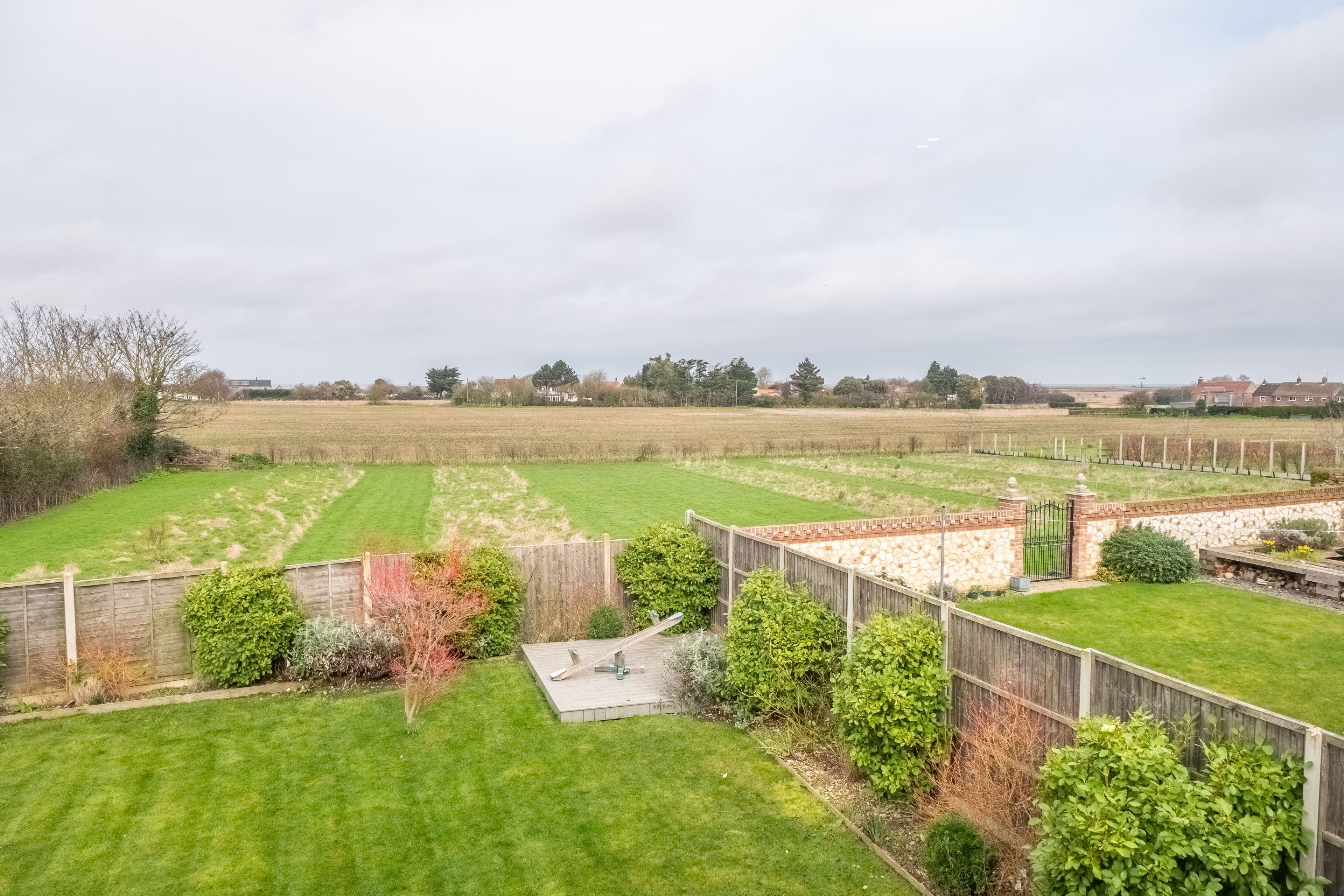 A spacious backyard with a wooden deck, a small garden area, and a stone wall.