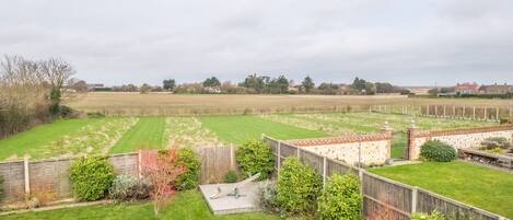 A spacious backyard with a wooden deck, a small garden area, and a stone wall.