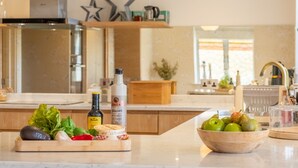 A kitchen counter with fresh produce, a bottle of olive oil, and a bowl of fruit.