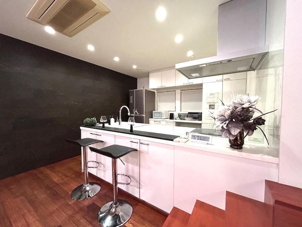 A modern kitchen with a central island, bar stools, and a decorative vase.