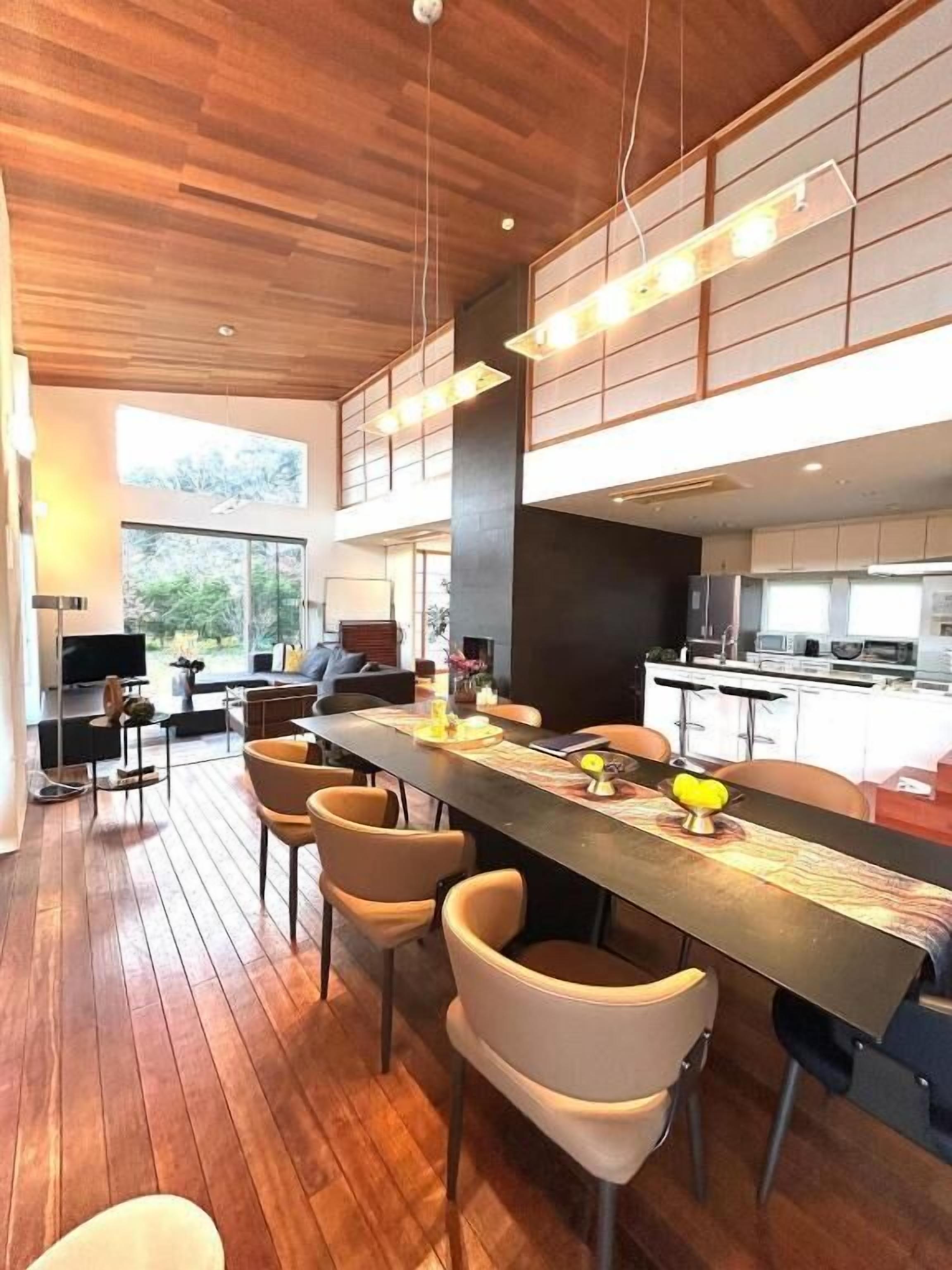 A modern kitchen with a long island, bar stools, and pendant lighting.