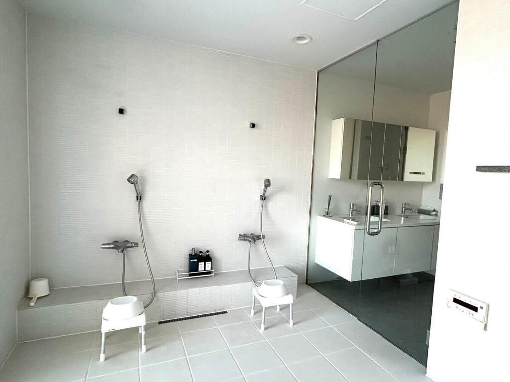 A modern bathroom with a glass shower enclosure, a white sink, and a mirror.