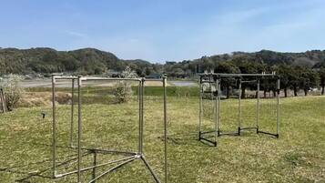 Two metal structures in an open field with a hilly landscape in the background.