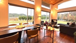 A modern interior with a dining area, seating, and large windows offering a view of the outdoors. - THE SATOYAMA HILLS　FK1 (Futtsu)