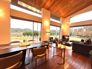 A modern interior with a dining area, seating, and large windows offering a view of the outdoors. - THE SATOYAMA HILLS　FK1 (Futtsu)