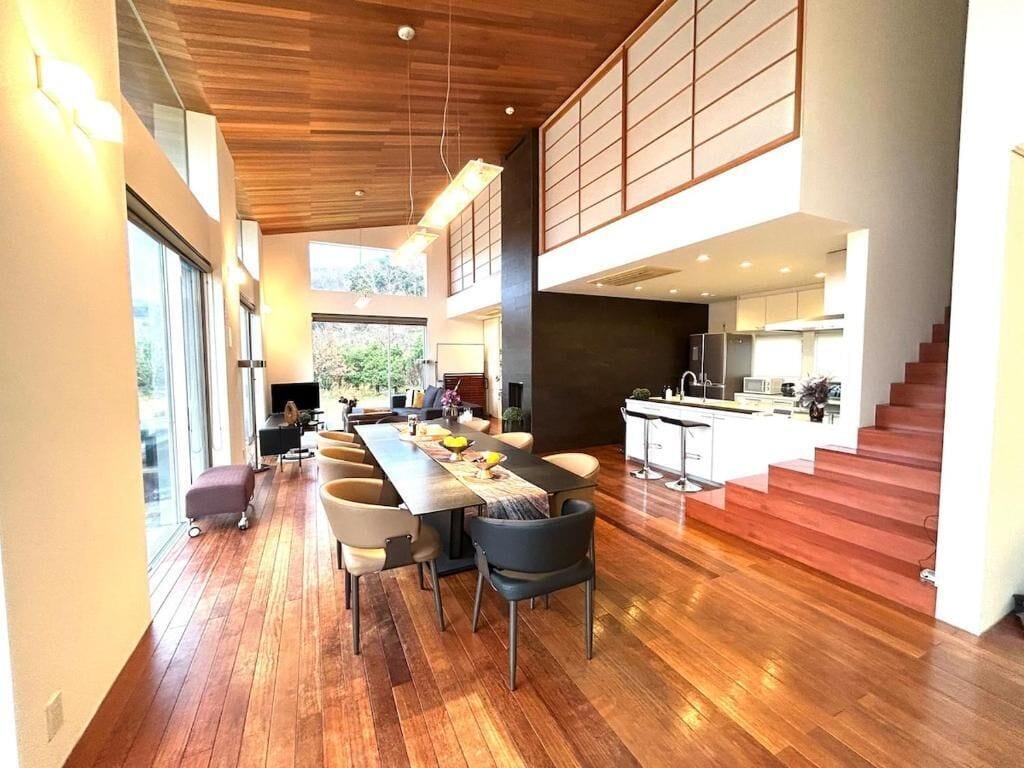 A modern interior with a dining area, kitchen, and staircase.