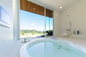 A modern bathroom with a large bathtub, a shower, and a view of the outdoors. - Futtsu Detached house (Futtsu)
