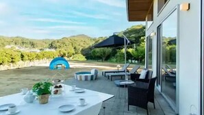 A patio with a table set for a meal, outdoor seating, and a view of the surrounding landscape. - THE SATOYAMA HILLS　FK1 (Futtsu)