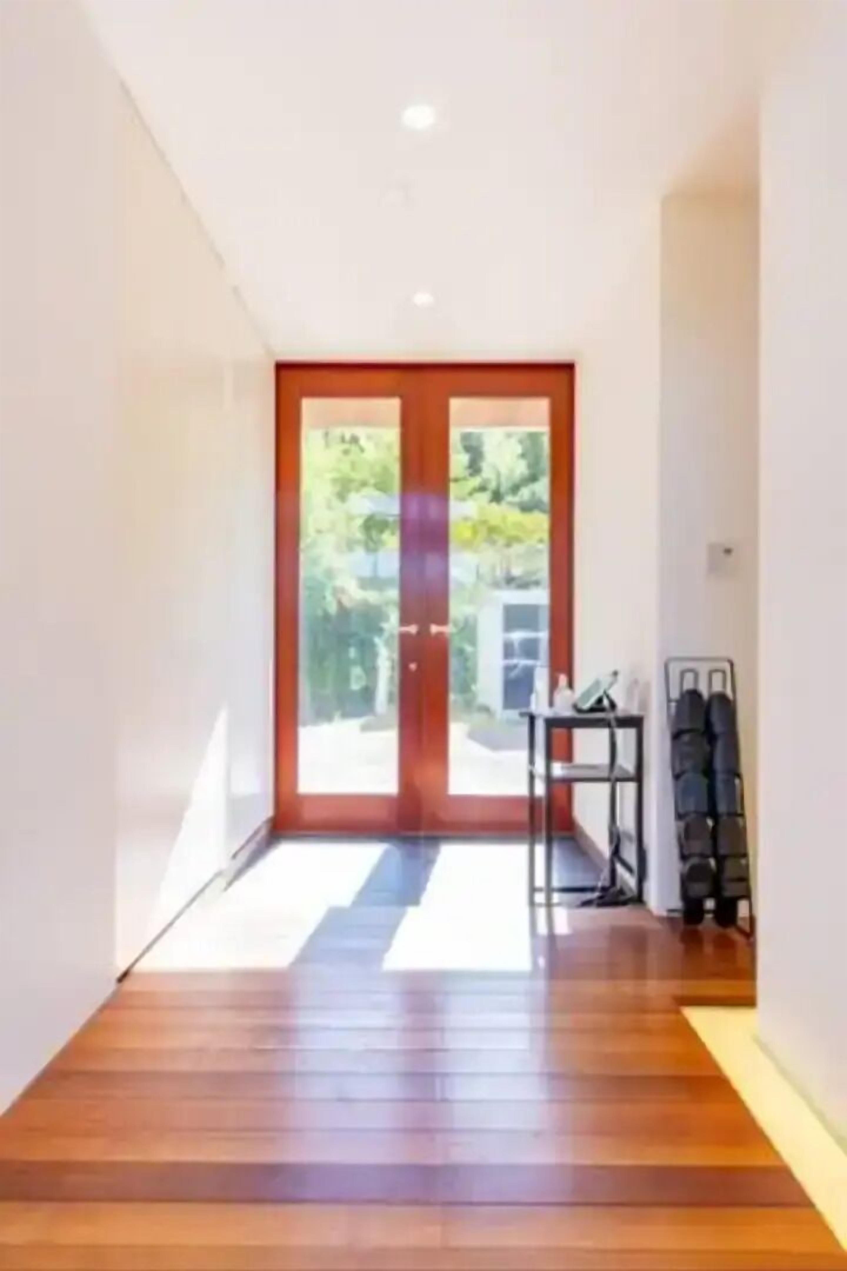 Un couloir doté d’un plancher en bois, une porte donnant sur l’extérieur et une petite table sur laquelle sont posés divers objets.