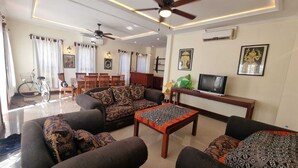 A living room with sofas, a coffee table, a TV, and a ceiling fan.