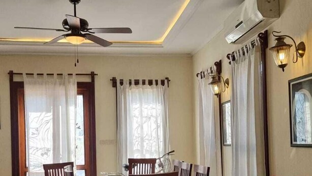 A dining area with a table, chairs, a ceiling fan, and a ceiling light fixture.
