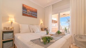 Une chambre à coucher avec un lit, des lampes de chevet, une table de chevet, une fenêtre avec des rideaux, un balcon et un tableau.
