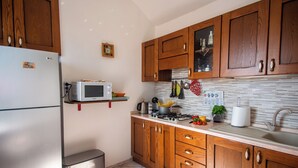 A kitchen with wooden cabinets, a microwave, a stove, and various kitchen items on the countertop. - Casa Felice Sanremo Centre Sea-View Apartment for 4, Sanremo, Italy (Sanremo)