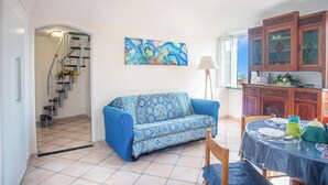 A living room with a sofa, a dining table with chairs, a staircase, and a kitchen area. - Casa Felice Sanremo Centre Sea-View Apartment for 4, Sanremo, Italy (Sanremo)