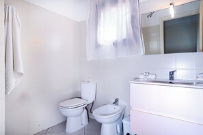 Ein Badezimmer mit Toilette, Bidet und Waschbecken mit Spiegel darüber.