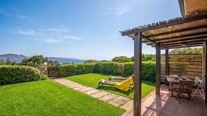 A patio with a view of the sea, a lawn, and a wooden pergola. - 1 Le Perle Di Stintino, Stintino, Italy (Stintino)
