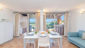 Un comedor con una mesa dispuesta para cuatro personas, un sofá y vistas a un balcón con mobiliario exterior.