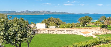 Un paisaje costero con vista despejada al mar, un área con césped y un edificio con patio amurallado.