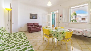 Una habitación con cama, una mesa de comedor con sillas, un sofá, una ventana con vistas y una puerta que da al exterior.