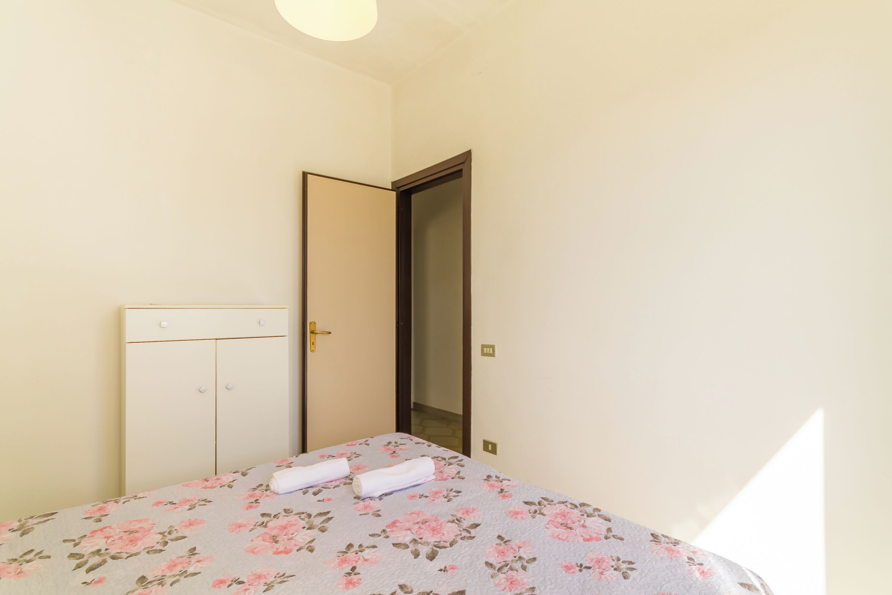 Une chambre à coucher comprenant un lit, une armoire et une porte donnant sur une autre pièce.