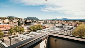 Une vue urbaine avec des immeubles, un parking et des montagnes en arrière-plan.
