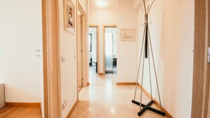 Un couloir doté d’un plancher en bois, d’un porte-manteau et d’œuvres d’art encadrées accrochées aux murs.