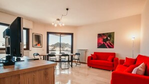 Un salon moderne avec un canapé rouge, une table basse en bois et un coin repas comprenant des chaises et une table.