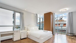 A modern bedroom with a large bed, a desk, and a view of the cityscape through large windows. - Losso Night Life D1 GymBarJapTown (Ho Chi Minh City)