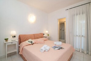 A neatly arranged hotel room with a bed, bedside tables, a lamp, a shower area, and a curtain. - Scoglietto 41 150m From The Sea, Costa Corallina, Italy (Costa Corallina)