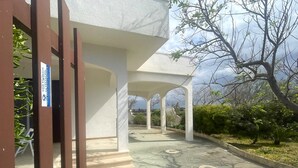A covered outdoor area with a concrete floor, white pillars, and a sign on the left.