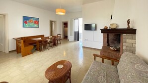 A spacious living area with a dining table, sofa, and fireplace.
