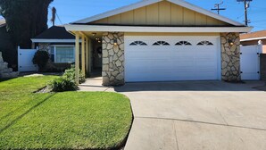 Une maison de plain-pied avec une façade en pierre, un garage et une pelouse bien entretenue.