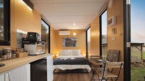 A compact room with a bed, a small kitchenette, and a dining area.