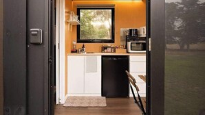 A modern kitchen with a large window, white cabinets, and a black dishwasher.