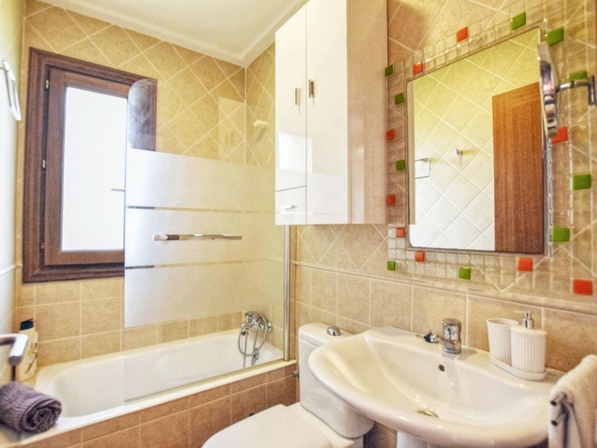 A bathroom with a bathtub, a sink, and a mirror.