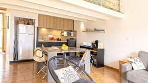 A modern kitchen with a dining area, a sofa, and a balcony. - Casa Sémaphore (L'Île-Rousse)