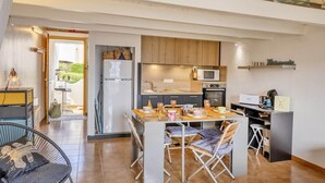 A modern kitchen with wooden cabinets, a microwave, and a dining area with a table and chairs. - Casa Sémaphore (L'Île-Rousse)