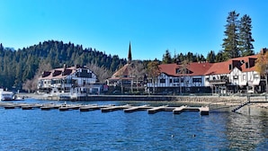 A lakeside town with traditional buildings, docks, and a forested hill in the background. - Emerald Lake View Loft (Lake Arrowhead)