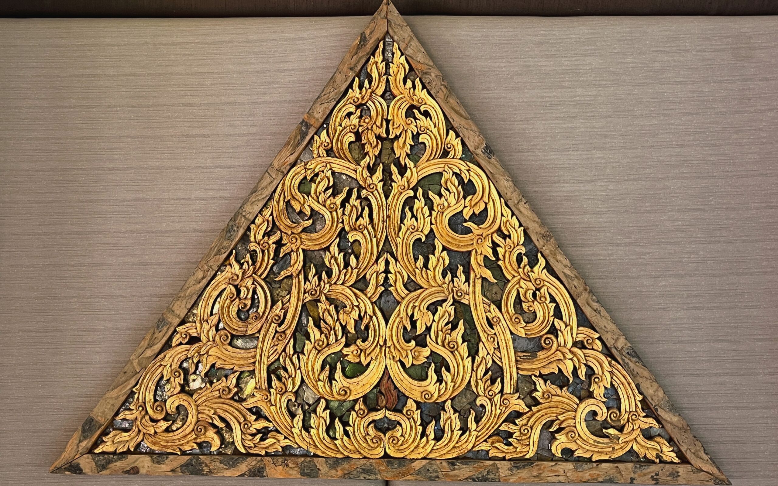 Un objeto triangular de madera con intrincados diseños dorados.