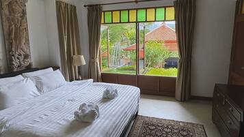 Una habitación de hotel con cama, ventana con cortinas, lámpara y cómoda.