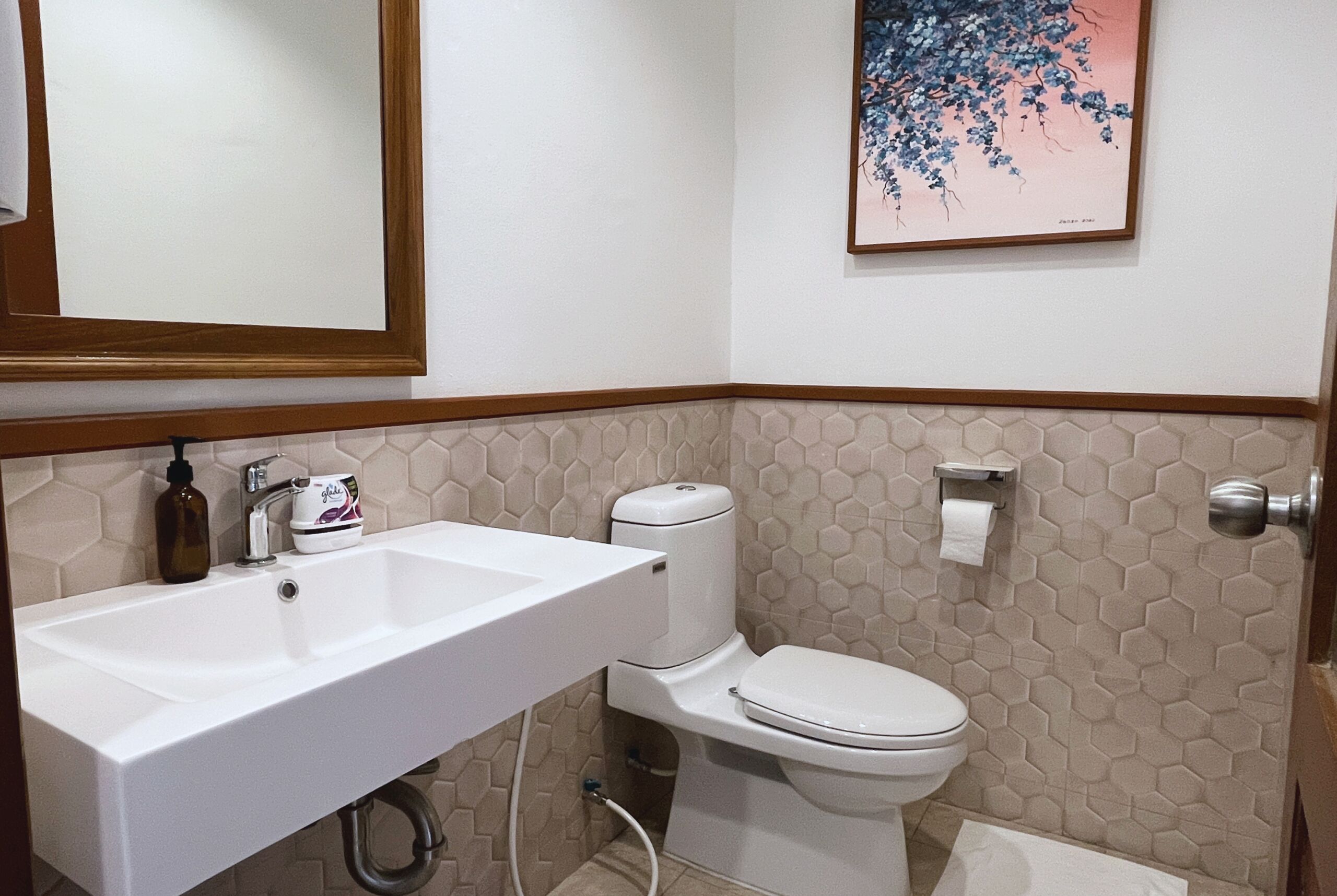 A bathroom with a white sink, toilet, and a framed picture on the wall.