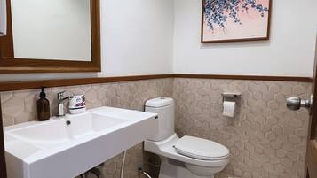 A bathroom with a white sink, toilet, and a framed picture on the wall.