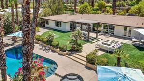 Una casa moderna con piscina, mobiliario de patio y un césped bien cuidado.