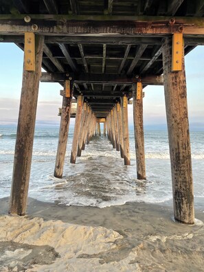 A wooden pier extending into the ocean with waves lapping at its base.