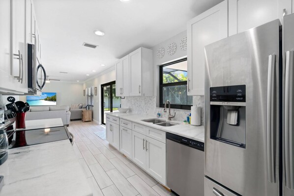A modern kitchen with stainless steel appliances, white cabinetry, and a built-in dishwasher.