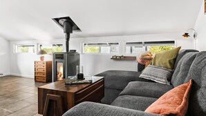 A cozy living room with a modern fireplace, a comfortable sofa, and a wooden side table with a book. - 2 bedroom nice home in Karrebæksminde (Karrebæksminde)
