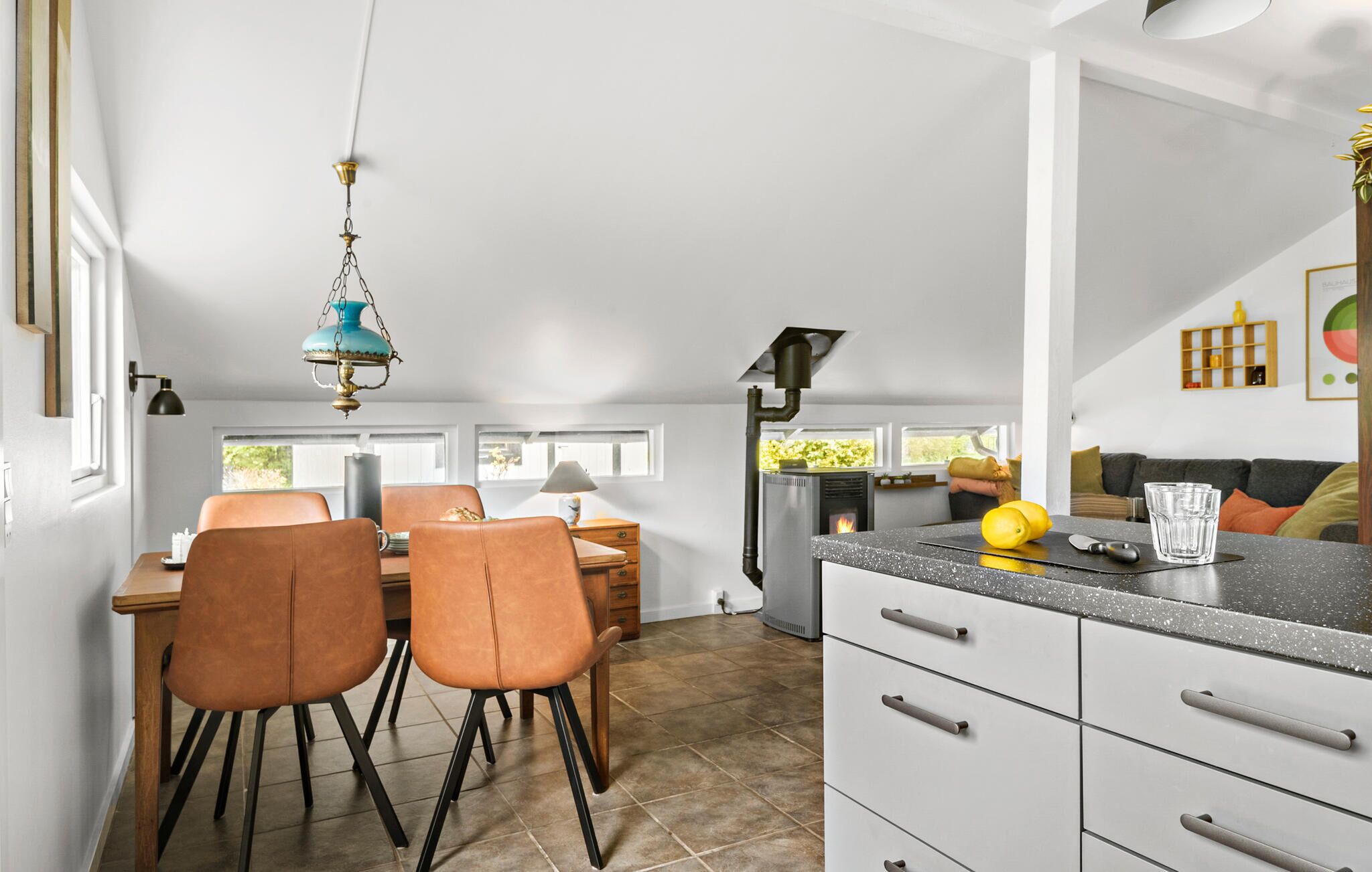 Een moderne keuken met een centraal eiland, een eethoek met twee stoelen en een groot raam dat voor daglicht zorgt.